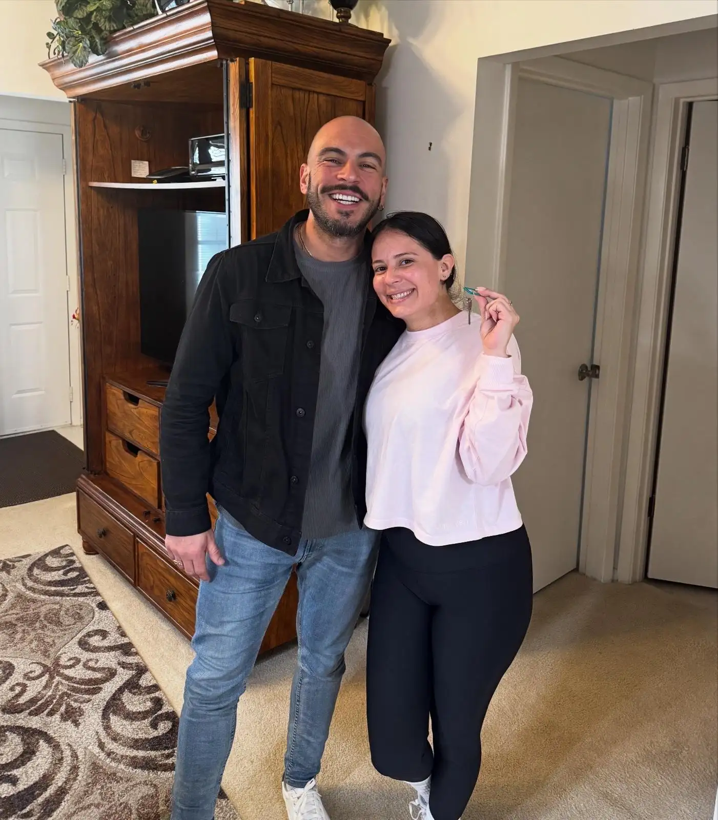 A new homeowner holding up the keys next to Jose inside the home